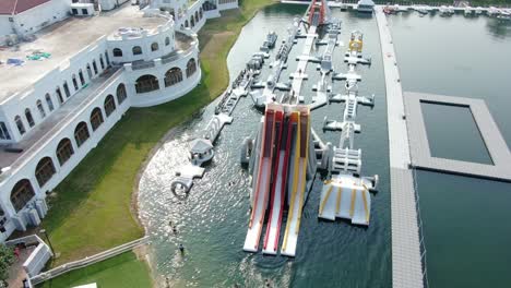 People-enjoying-a-sunny-day-at-Hong-Kong-core-aqua-park-floating-fun-slides,-Aerial-view