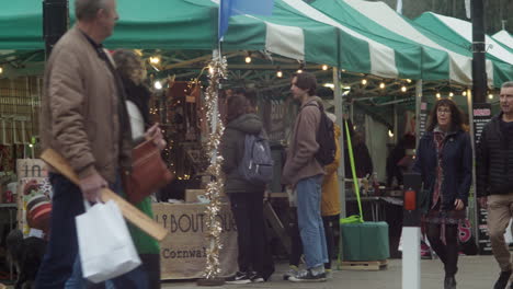 Gente-Comprando-Y-Caminando-En-Un-Mercado-De-Granjeros-En-La-Ciudad-De-Truro,-Cornualles,-Inglaterra,-Reino-Unido,-Tiro-Panorámico-En-Cámara-Lenta