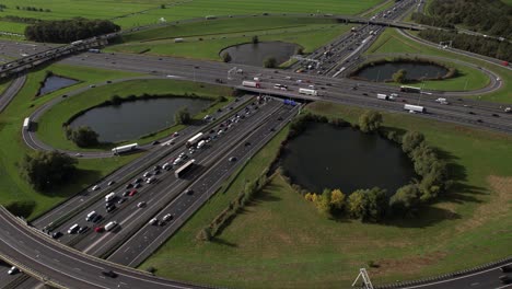 Movimiento-Hacia-Atrás-Que-Revela-Una-Gran-Rotonda-De-Intersección-De-Circunvalación-De-Oudenrijn-Cerca-De-Utrecht-Con-Vehículos-Lentos-Vistos-Desde-Arriba-Con-Ominosos-Cúmulos-Oscuros-Colgando-Sobre-él