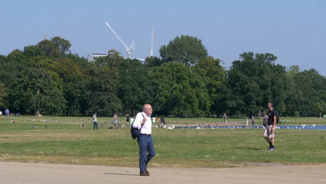 Hombre-De-Mediana-Edad-Caminando-Alrededor-Del-Estanque-Del-Jardín-De-Kensington-En-Londres,-Reino-Unido