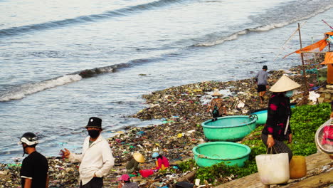 Aldeanos-Vietnamitas-Caminando-Por-La-Orilla-De-Una-Playa-Contaminada-Llena-De-Basura