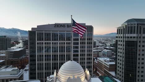 Hermosa-Toma-Aérea-Que-Muestra-La-Bandera-Estadounidense-Ondeando-En-El-Centro-De-Salt-Lake-City-Utah---Movimiento-Orbital