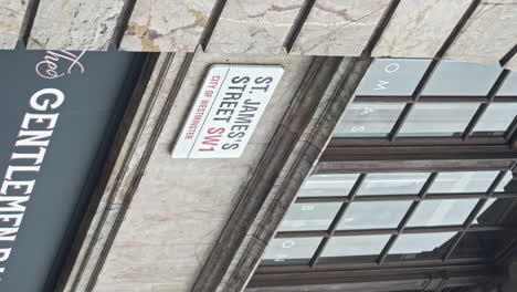 Vídeo-Vertical-En-Cámara-Lenta-Que-Revela-Una-Toma-De-La-Calle-St-James-SW1,-Letrero-De-La-Calle-En-Un-Antiguo-Edificio-De-Mármol-Con-Ventanas-De-Madera