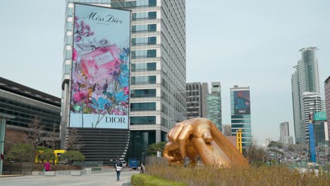 Statue-Mit-Goldenen-Händen-Im-Gangnam-Stil-Im-Coex-Geschäftskomplex-Und-Riesige-Werbeanzeige-Auf-Dem-Asem-Tower-In-Seoul-–-Totale