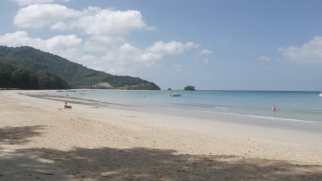 the-beach-with-a-few-yachts-in-sea,-white-sand-and-wave-from-peaceful-sea-in-sunshine-daytime