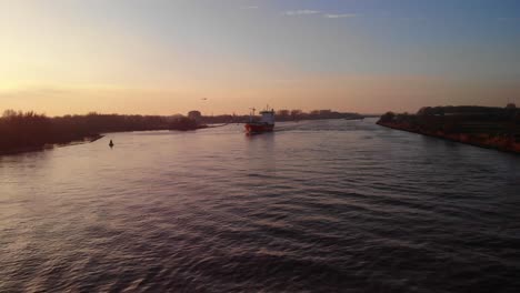 Aerial-View-Of-A2B-Ambition-Cargo-Ship-Navigation-Oude-Maas-With-Golden-Yellow-Sunset-Skies