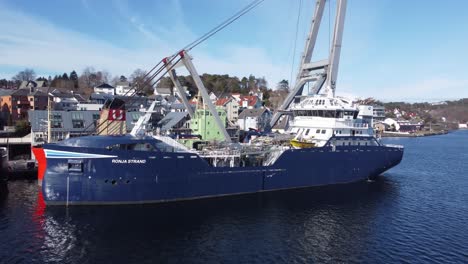 Fish-carrier-Ronja-Strand-from-solvtrans-company-is-moored-alongside-in-Leirvik-Harbor-Norway---Beautiful-aerial-with-sunlight-and-reflections-on-vessel-hull