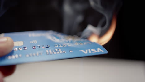 A-VISA-credit-card-catches-fire-while-held-in-a-hand,-many-concepts