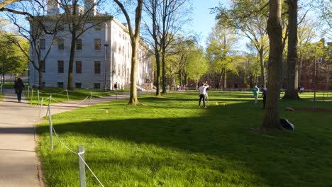 Estudiante-Caminando-Por-El-Patio-De-Harvard,-Mirando-A-Otras-Personas-Caminando-Y-Jugando-En-El-Exterior-Del-Campus