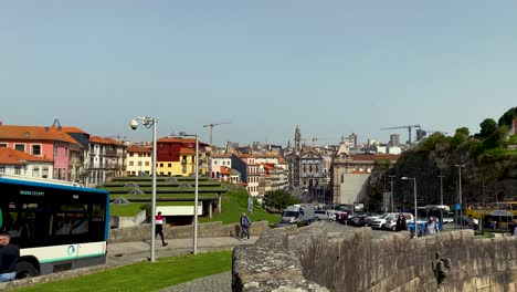 Toma-En-Cámara-Lenta-De-Conducir-Un-Autobús-Y-Caminar-A-La-Gente-En-La-Carretera-De-Oporto-Durante-El-Día-Soleado-Con-Edificios-En-Segundo-Plano