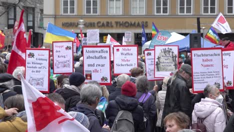 Anti-war-demonstrators-gathering-in-Marienplatz,-Munich,-Bavaria,-Germany-holding-placards-and-flags