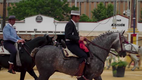 Spanish-men-in-Jinete-outfits-ride-horses-at-Jerez-Fair-in-Spain,-Pan-Right