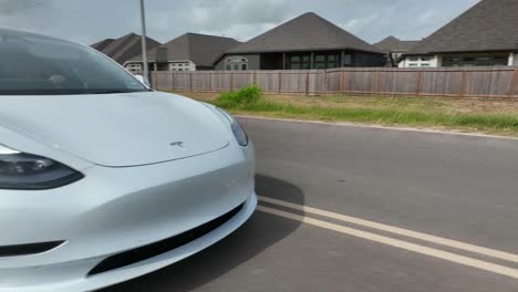 Primer-Plano-De-Seguimiento-Del-Emblema-Del-Logotipo-De-Tesla-En-El-Coche-Eléctrico-Modelo-3