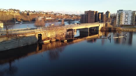 Puente-Entre-Las-Islas-Smieoya-Y-Klosteroya-En-El-Canal-De-Telemark-Skien-Noruega---Automóviles-Pasando-Por-El-Puente-Durante-Las-Horas-Del-Atardecer-Con-Hermosos-Reflejos-En-La-Superficie-Del-Agua