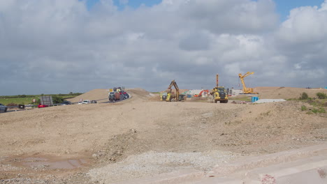 Traffic-Driving-In-The-Highway-Along-The-Construction-Site-Of-New-Road-With-Heavy-Equipments,-Cornwall---wide