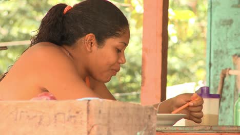 Indigenous-woman-eating-from-a-bowl-at-the-community-kitchen-in-a-village-near-Manaus,-Brail