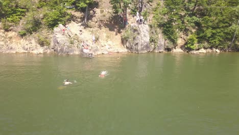 Drone-view-of-people-playing-and-swimming-in-warm-lake-and-on-shore-tanning