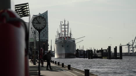 Tourists-walking-at-Hamburg-Harbor-with-Elbphilharmonie-in-the-back-at-Landungsbrücken