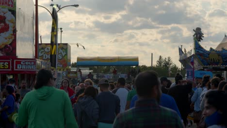 Una-Multitud-De-Asistentes-A-La-Feria-Caminando-Por-El-Recinto-Ferial,-A-Través-De-Una-Gran-Multitud-De-Otras-Personas-Que-Deambulan