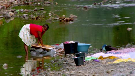 Eine-Afrikanische-Frau-Aus-São-Tomé-Arbeitet-Hart-Daran,-Wäsche-Am-Fluss-Zu-Waschen