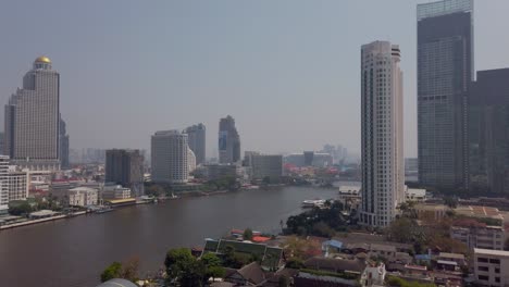 Zeitlupenansicht-Des-Flusses-Chao-Phraya-In-Bangkok-Mit-Bangkok-Higrise-Gebäude-Am-Ufer-Des-Flusses