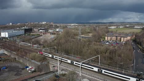 Aerial-footage-of-trains-approaching-Stoke-on-Trent-train-station-in-the-midlands-by-the-canal,-waterside-and-A50-motorway