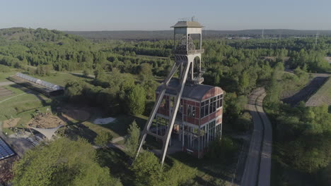 Toma-Aérea-De-Sobrevuelo-De-Una-Antigua-Torre-De-Pozo-De-Mina-En-Un-Fondo-Forestal