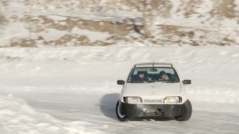 Ein-Auto,-Das-Während-Einer-Professionellen-Motorsportveranstaltung-Auf-Der-Isola-2000-In-Zeitlupe-Auf-Einer-Rutschigen,-Verschneiten-Rennstrecke-Im-Winter-Driftet,-Während-Die-Reifen-In-Der-Kurve-Durchdrehen