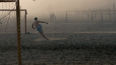 Junger-Mann-Kickt-Fußball-Mitten-In-Der-Luft-Mit-Scherenstoß,-Während-Dichter-Meeresnebel-Das-Spielfeld-Bedeckt