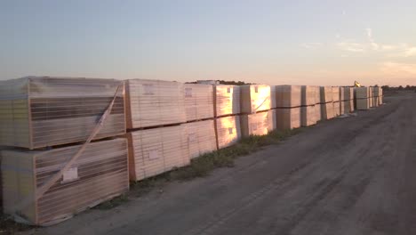 Drone-shot-of-a-wooden-insulation-panels-pallet-on-the-ground-during-sunset