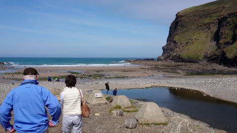 Ein-Paar-ältere-Touristen-Halten-Am-Crackington-Haven-Beach-In-Cornwall,-Vereinigtes-Königreich,-Wo-Spaziergänger,-Schwimmer-Und-Badegäste-Spaß-Haben