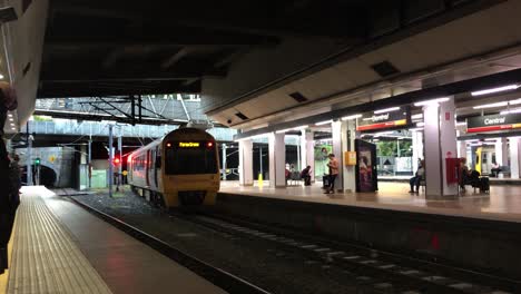 A-Queensland-Rail-train-leaves-the-station-and-enters-a-tunnel,-at-Central-Station,-Brisbane,-Australia