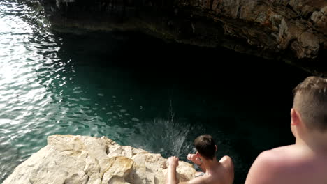 Un-Joven-Hace-Un-Salto-Hacia-Atrás-Desde-Un-Alto-Acantilado-Hacia-El-Agua.