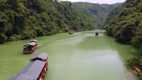 Zhangjiajie,-China---Agosto-De-2019:-Barcos-De-Madera-Tradicionales-Que-Navegan-En-Las-Aguas-De-Un-Pequeño-Lago-Estrecho-Entre-Acantilados-Rocosos-Altos-Y-Altos-Del-Majestuoso-Gran-Cañón-En-El-Parque-Nacional-De-Zhangjiajie