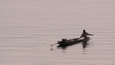 Fisherman-silhouetting-as-he-is-casting-and-drawing-his-net-in-the-River-before-dark