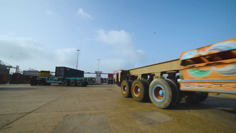 Trucks-entering-into-the-port,-A-long-vehicle-traller-is-moving-on-the-road-of-a-port,-camera-passing,-close-up-view