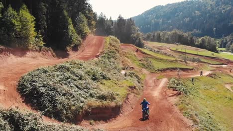 Drohnenaufnahme-Von-Motocross-Fahrern-Auf-Motorrädern-Auf-Unbefestigter-Parkstrecke,-Die-Springen-Und-Spaß-Haben