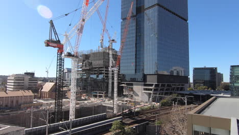 Hiperlapso-De-Grandes-Edificios-En-Construcción-Junto-A-La-Estación-De-Tren-De-Parramatta-Que-Muestra-Grúas,-Hombres-Y-Vehículos-Moviéndose-Alrededor-Del-Sitio-De-Construcción