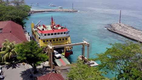 Port-Roro-Con-Ferry-De-Vehículos-Nusa-Jaya-Abadi-Descargando-Motocicletas-Y-Vehículos-Con-Origen-En-Bali,-Toma-Aérea-Izquierda-Revelada