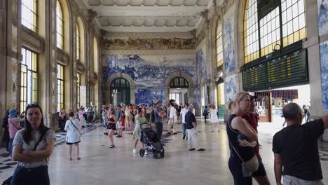 Tilt-down-from-ceiling-to-wide-shot-inside-busy-Sao-Bento-Train-Station-in-Porto,-Portugal