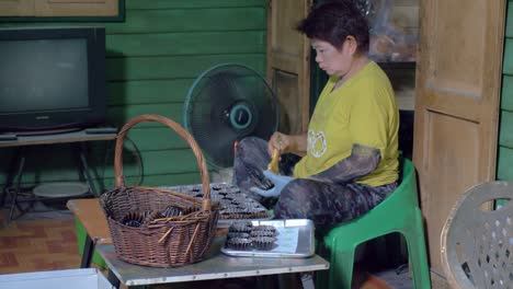 Bakery-worker-taking-cupcake-liners-from-basket-and-greasing-them-with-pastry-brush