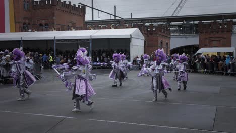 Group-of-parade-performers-dancing-and-shaking-sticks-in-purple-costumes