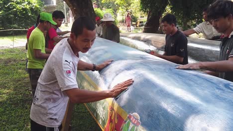 Medium-Slow-Motion-Shot-of-a-Group-of-Men-Sanding-the-Bottom-of-a-Boat