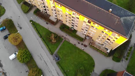 Top-down-aerial-drone-view-of-block-buildings-rooftops-and-parking-lot,-forward