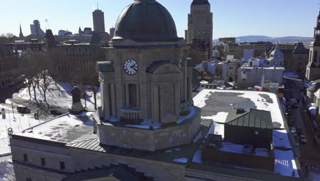 Un-Dron-Vuela-Desde-La-Torre-Del-Reloj-Con-Una-Bandera-Canadiense-Para-Revelar-El-Castillo-Frontenac-Cubierto-De-Nieve