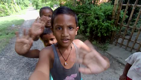 Poor-Asian-boy-holds-the-camera-and-all-children-smiling-and-waving-hands,-slow-motion-shot