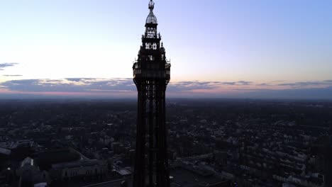 Blackpool-tower-aerial-view-high-night-coastal-seaside-resort-landmark-tourist-attraction-tilt-down-to-town-buildings