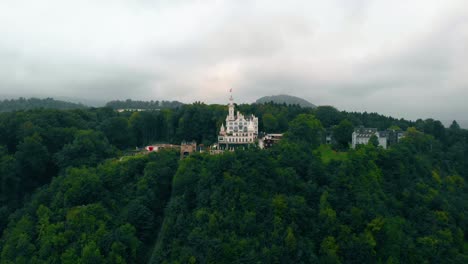 Vista-Aérea-Sobre-El-Bosque-Hacia-El-Castillo-Chateau-Gutsch-Y-El-Hotel-De-Lujo,-Oscuro,-Sombrío,-Día-De-Verano,-En-Luzern,-Suiza---Levantamiento,-Disparo-De-Drones