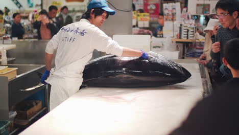 Hombre-Colocando-El-Atún-Rojo-En-Una-Mesa-Blanca-Lista-Para-Diseccionar-Con-La-Audiencia-En-El-Mercado-De-Pescado-Toretor-Ichiba,-Wakayama-Japón