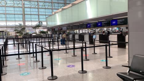 Empty-airport-check-in-line-due-to-coronavirus-pandemic,-masked-girl